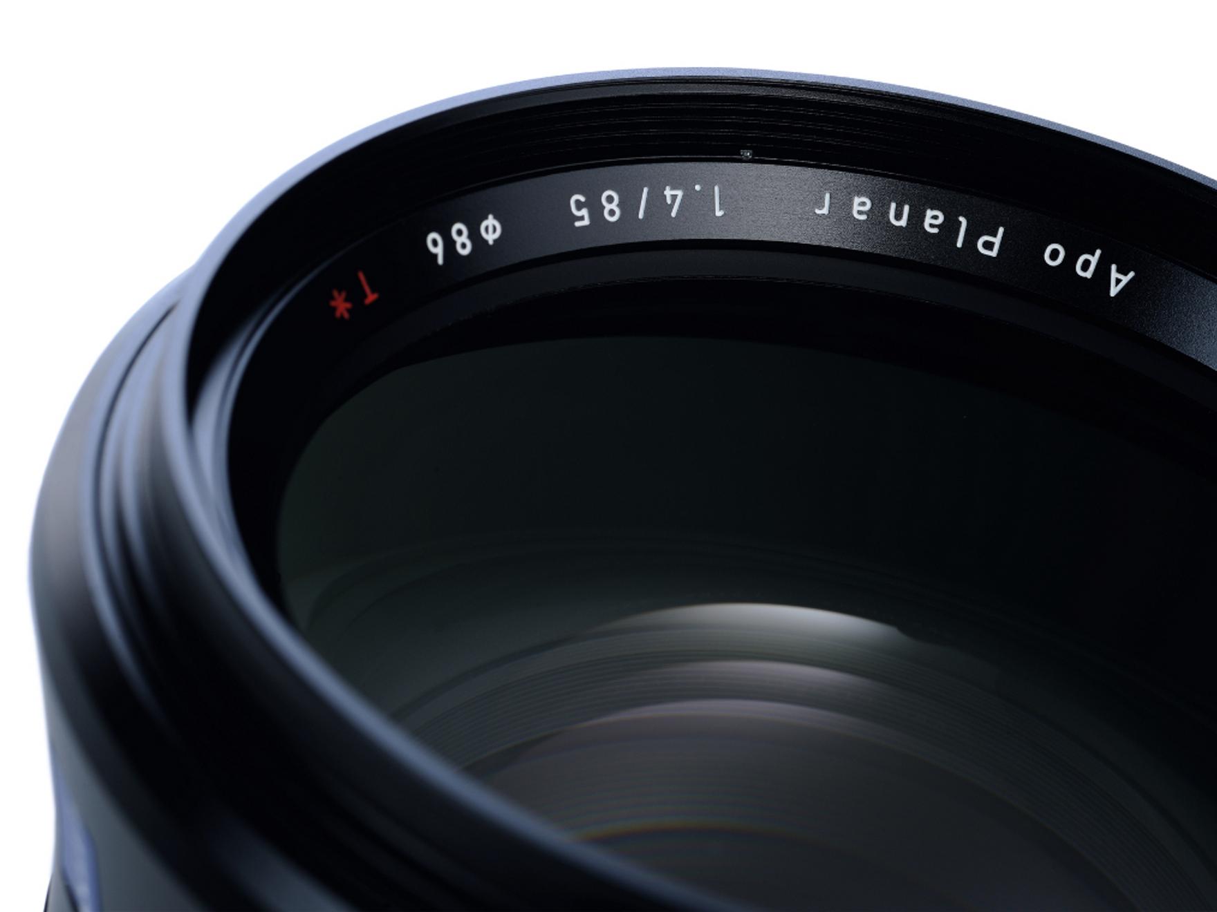 Close-up view of a ZEISS Apo Planar 85mm f/1.4 camera lens showing detailed lens glass and engraved specifications.