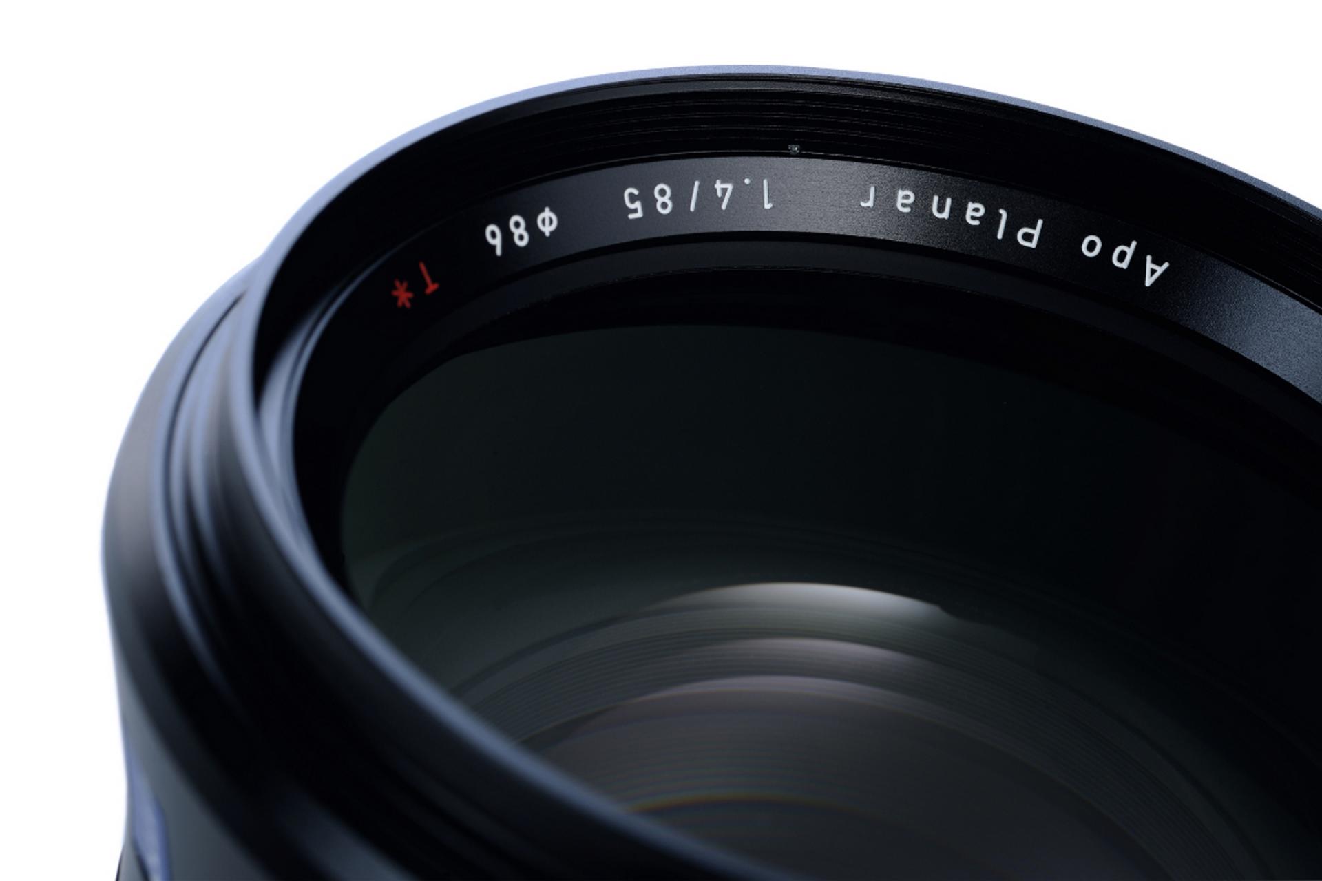 Close-up view of a ZEISS Apo Planar 85mm f/1.4 camera lens showing detailed lens glass and engraved specifications.