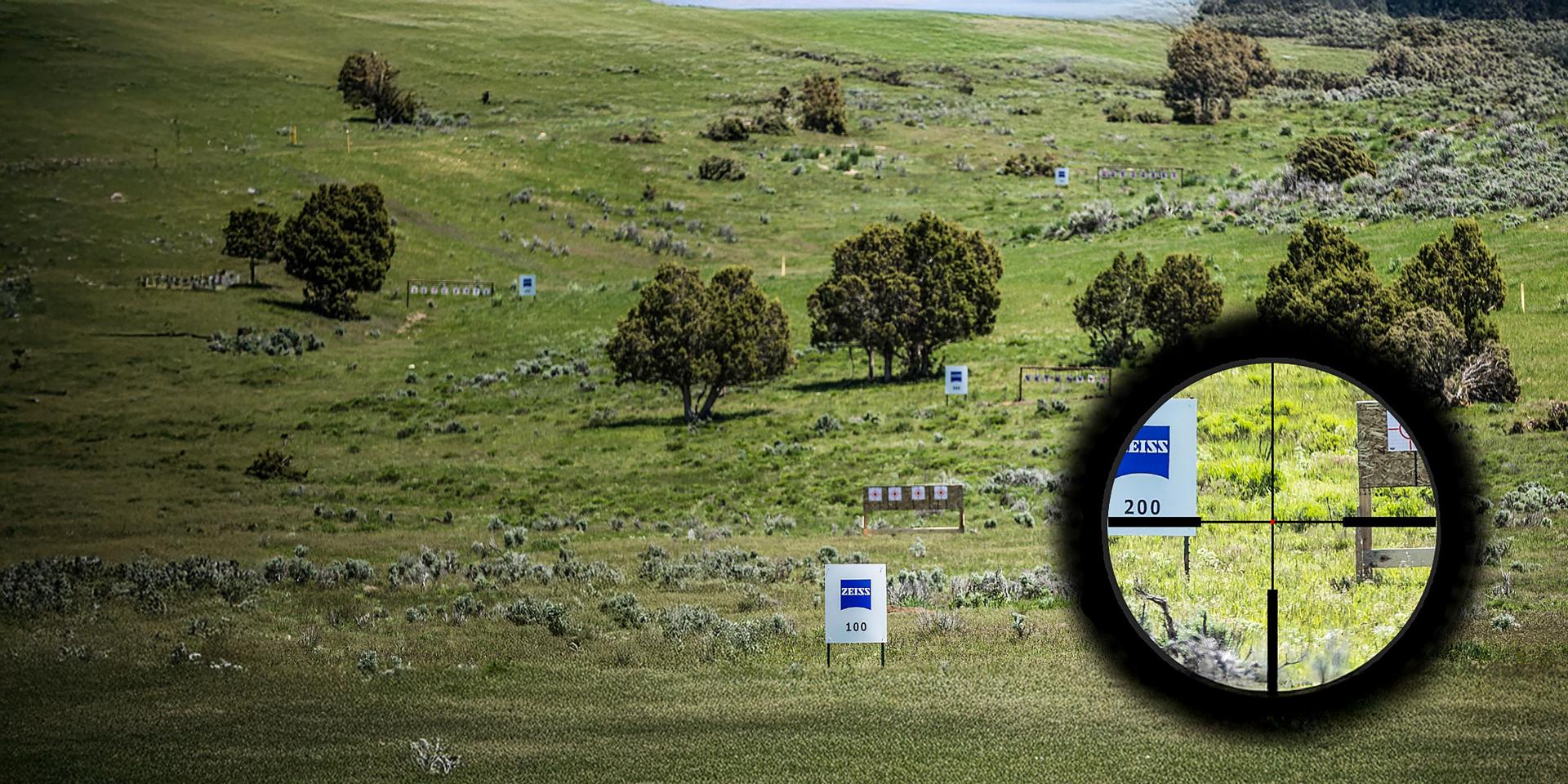 A grassy shooting range with multiple target signs, including ZEISS-labeled distance markers, viewed through the reticle of a ZEISS rifle scope.