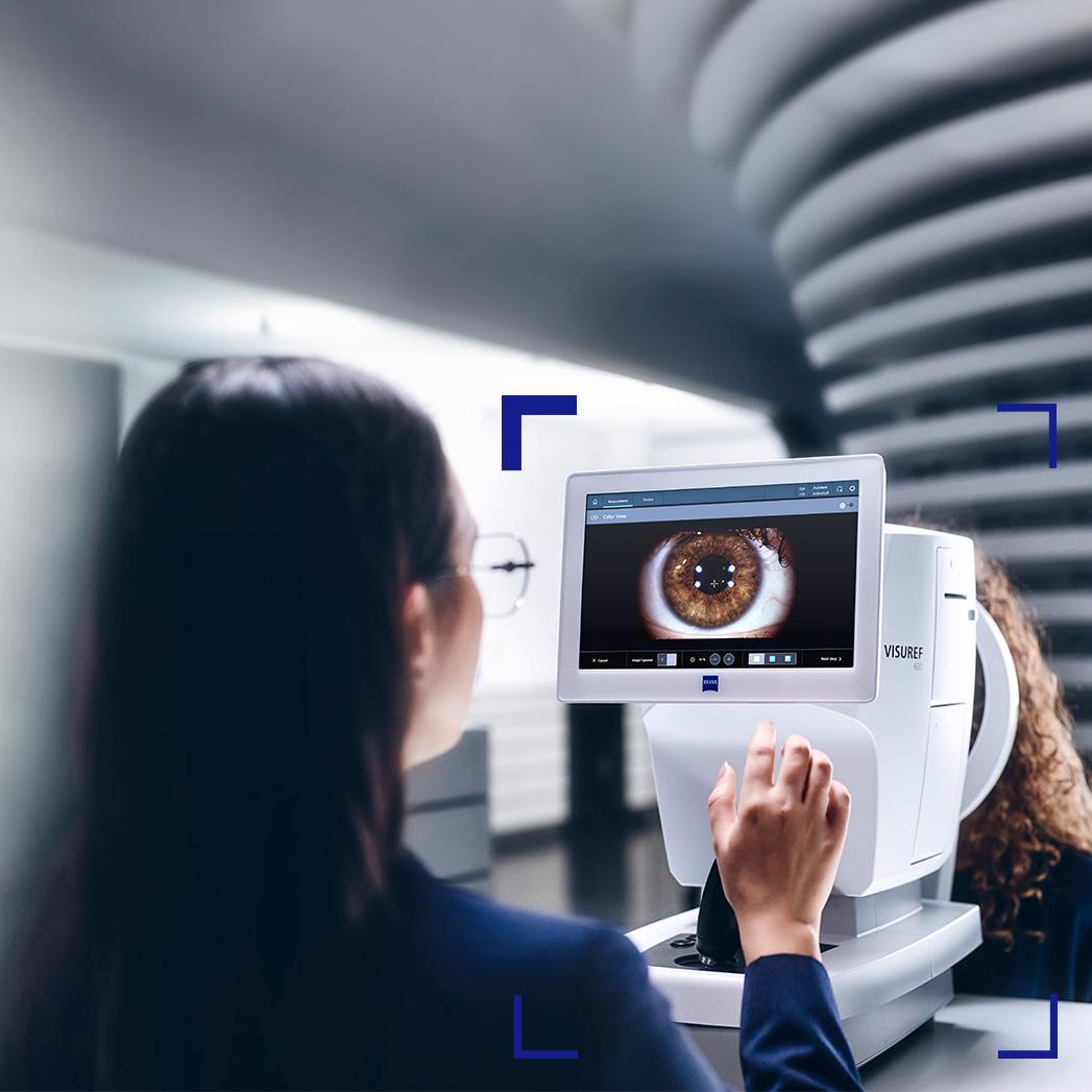 A female optician looking at the ZEISS VISUREF 600 screen showing an image of an eye.