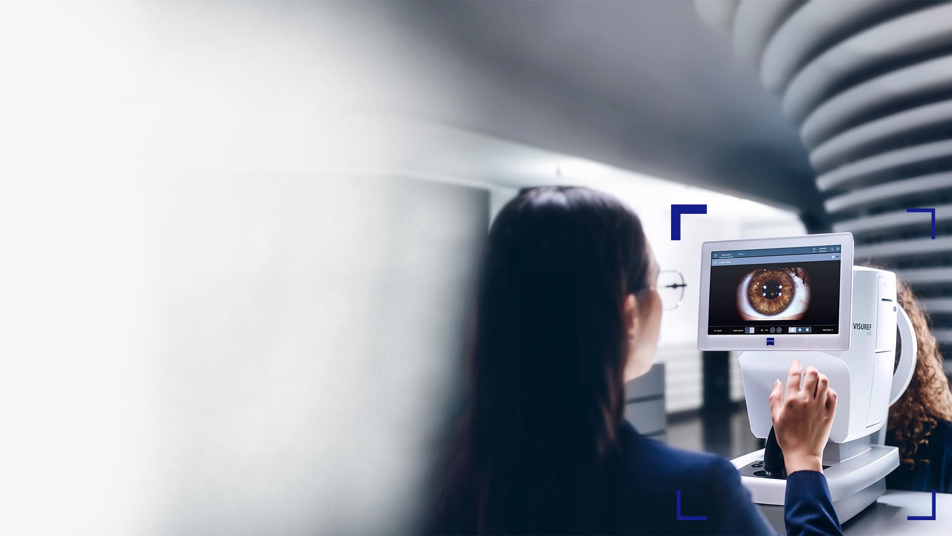 A female optician looking at the ZEISS VISUREF 600 screen showing an image of an eye.
