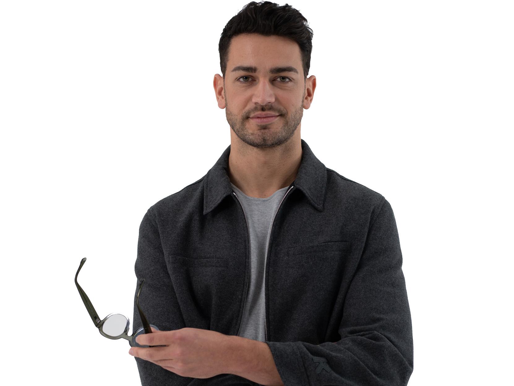 oung man with short brown hair smiling in camera holding glasses in his hand.