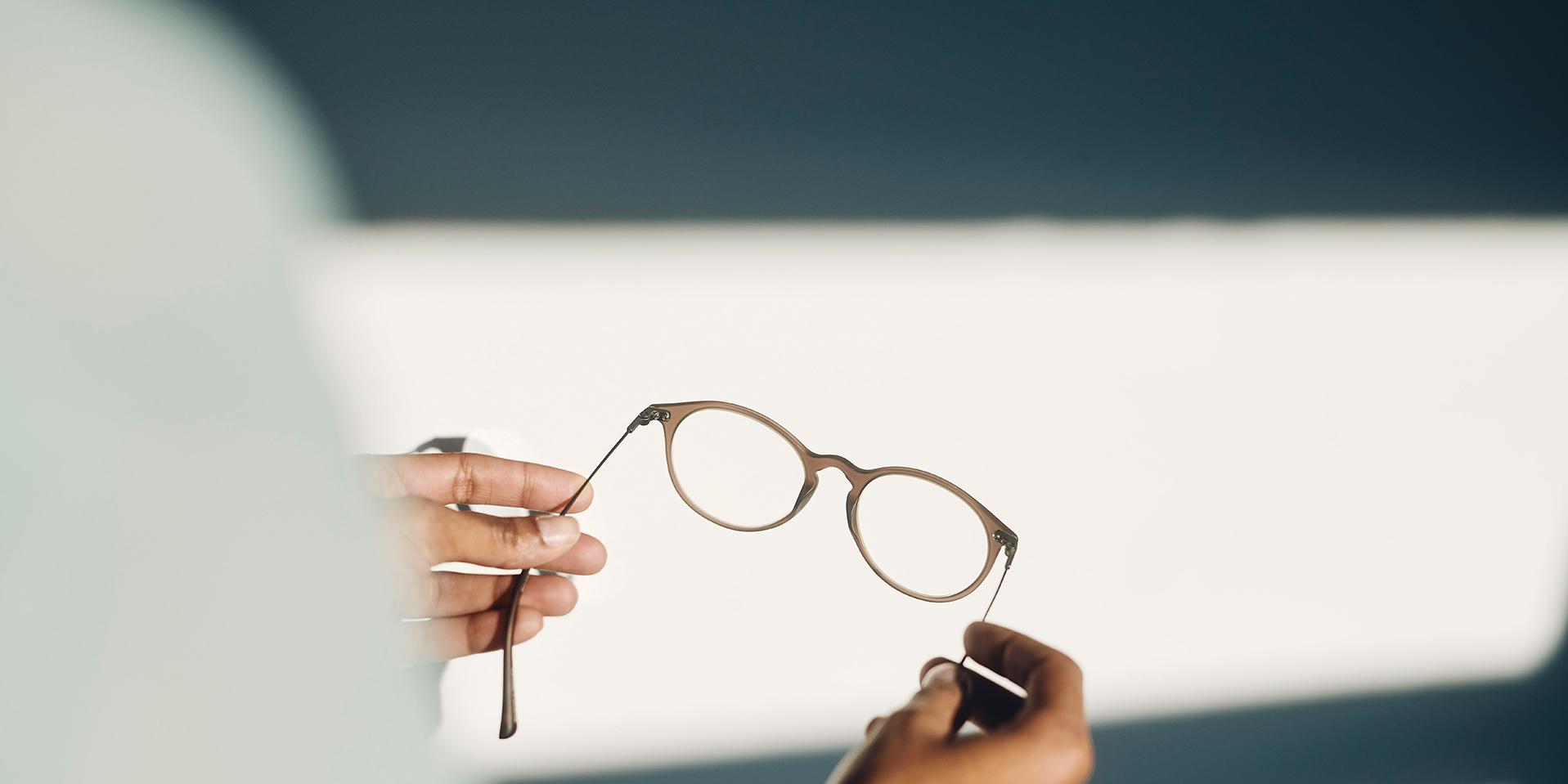 An optician handing eyeglasses to a customer.
