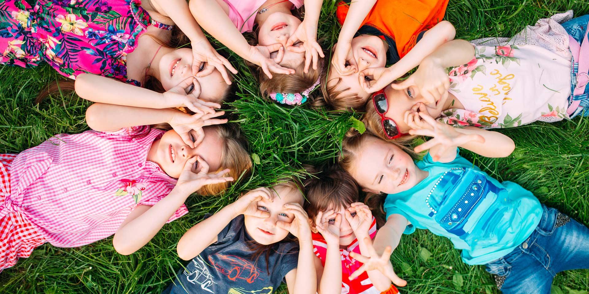 A group of children lying on the green grass in the park. The interaction of the children.