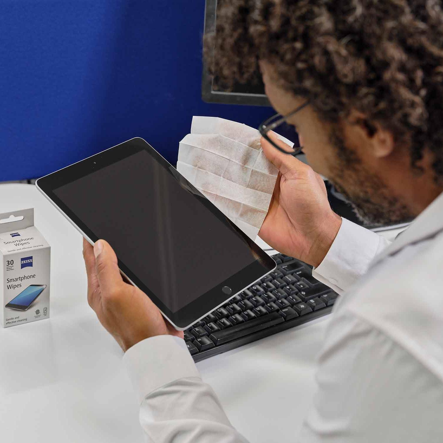 Man cleaning tablet display with smartphone wipes