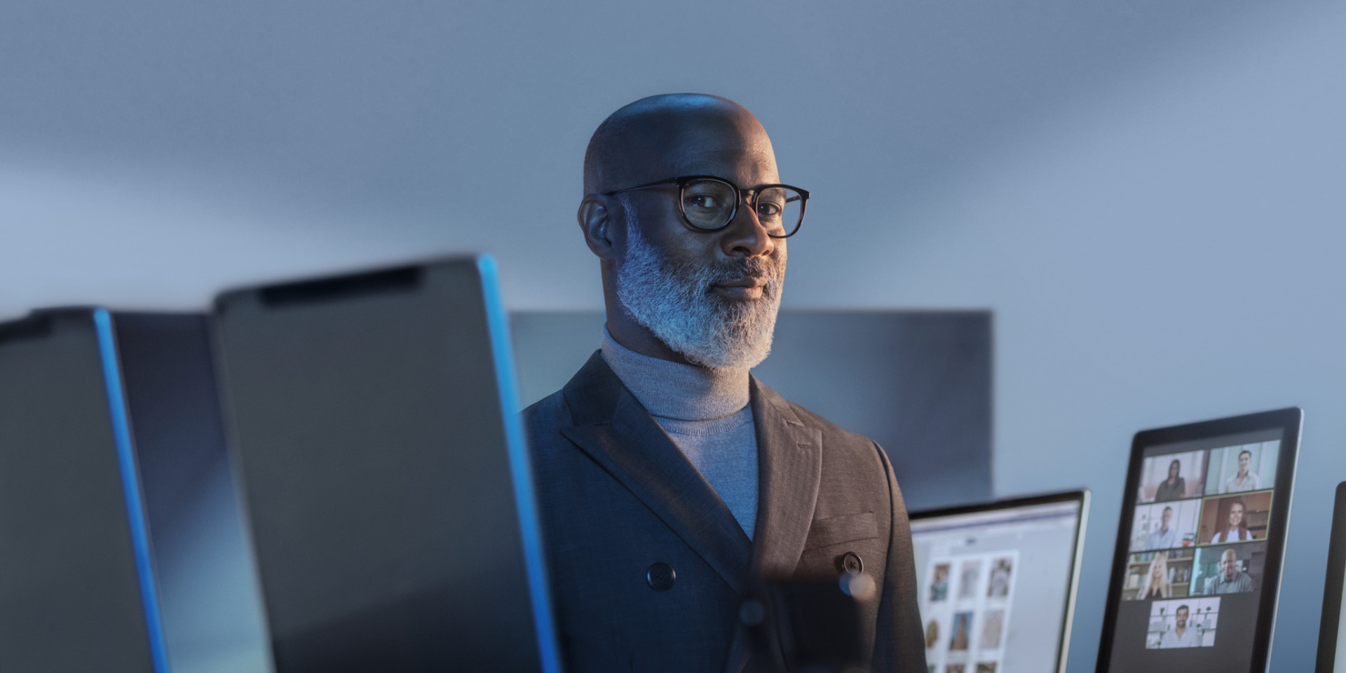 Smiling man surrounded by digital devices wearing glasses with ZEISS BlueGuard for blue light protection.