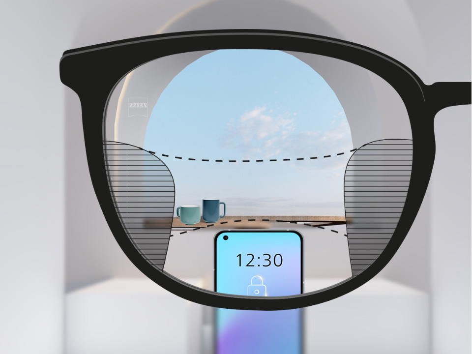 A point of view image with ZEISS Progressive SmartLife lenses with a smartphone and cups in the background while the lens is fully clear with slim blurry plots left and right.